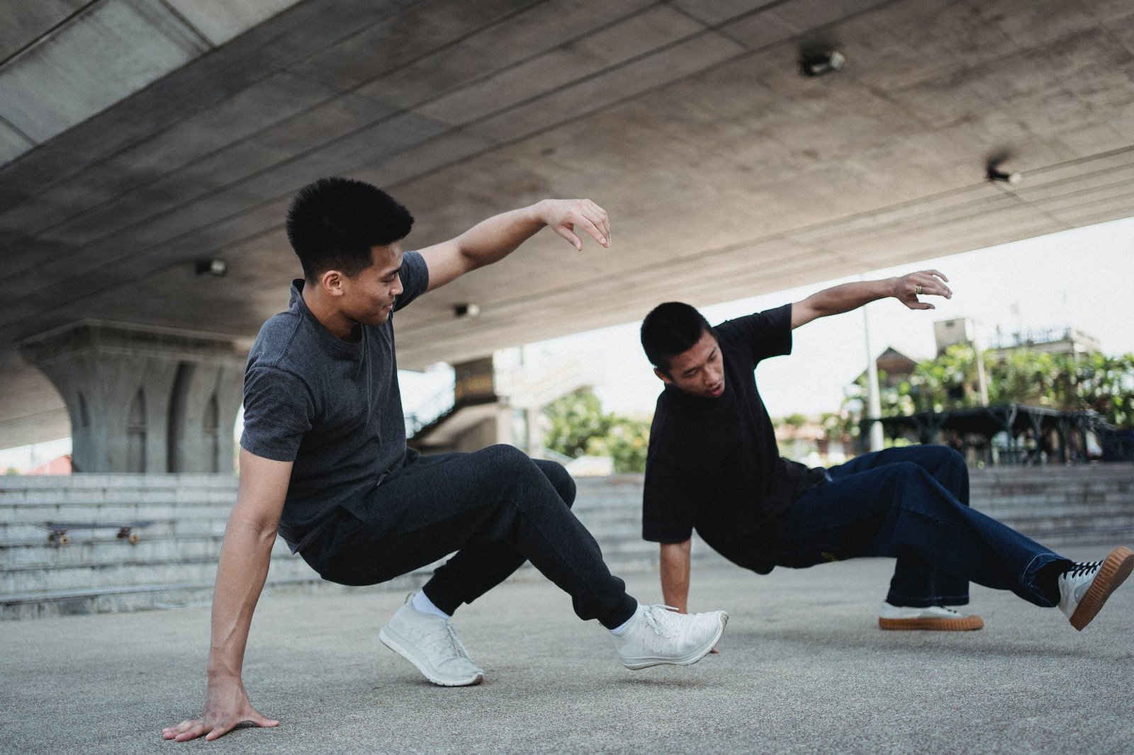 energetic asian men performing breakdance under elevated highway
